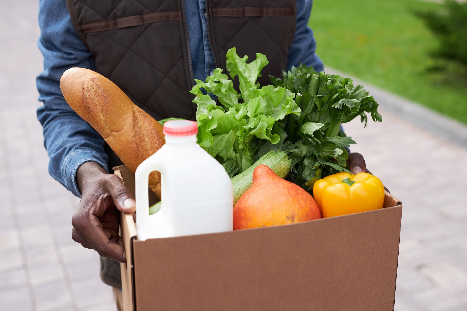 Closeup of black man carrying box with fresh vegetables